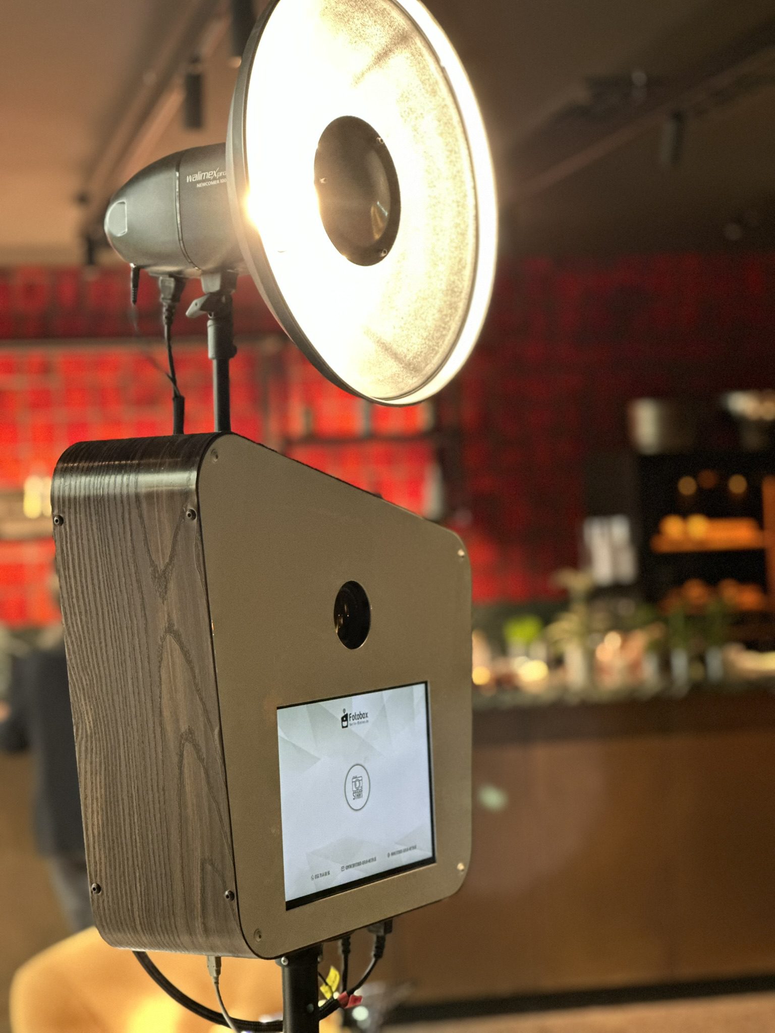 Edle Fotobox mit Holzakzenten und weißem Beauty-Dish-Reflektor in einer Berliner Event-Location für eine Firmenfeier.